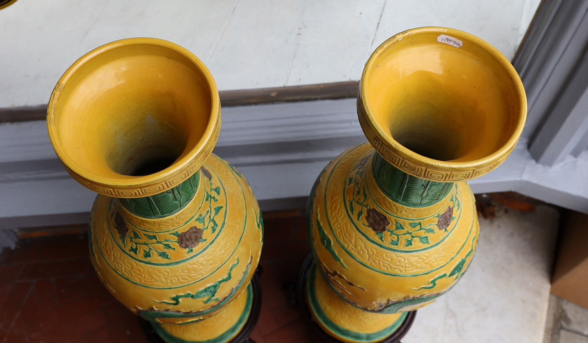 A pair of Chinese yellow glazed baluster vases decorated with bands of flowers and dragons, on hardwood stands, height 67cm. height overall 85cm
